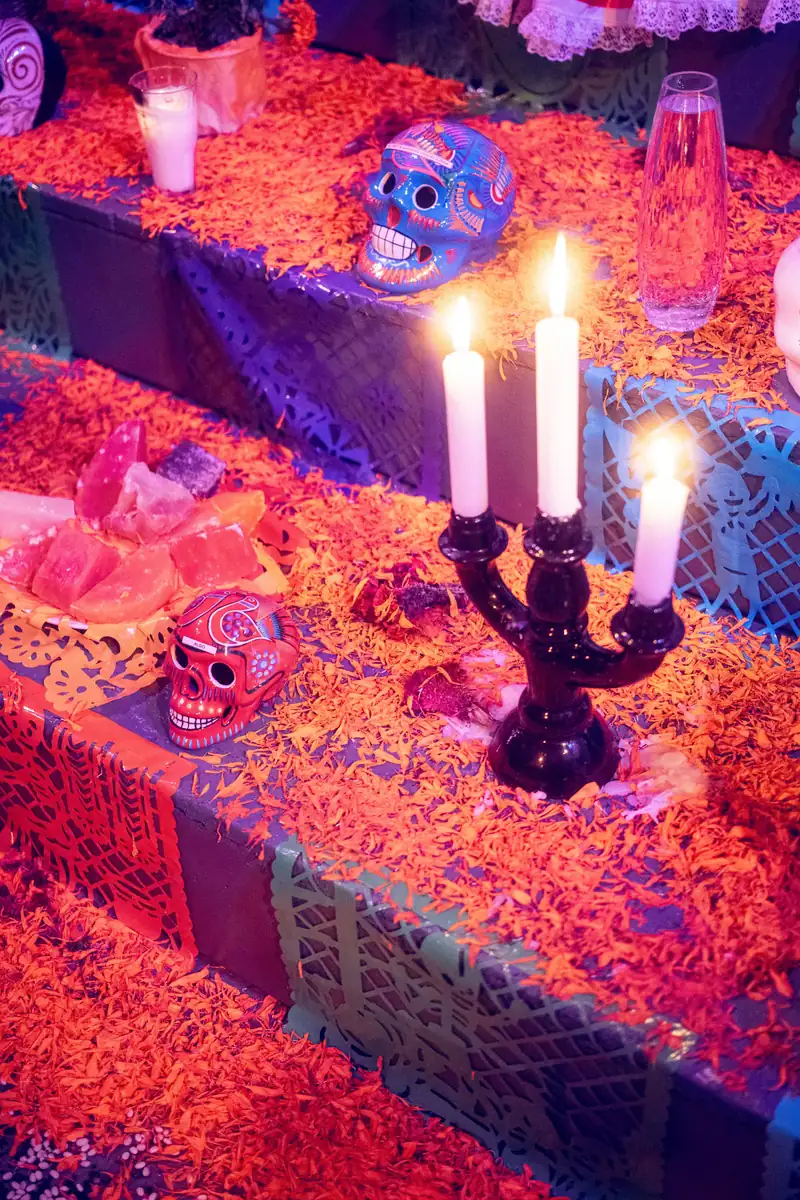 A Día de los Muertos altar with lit candles, sugar skulls and marigold petals