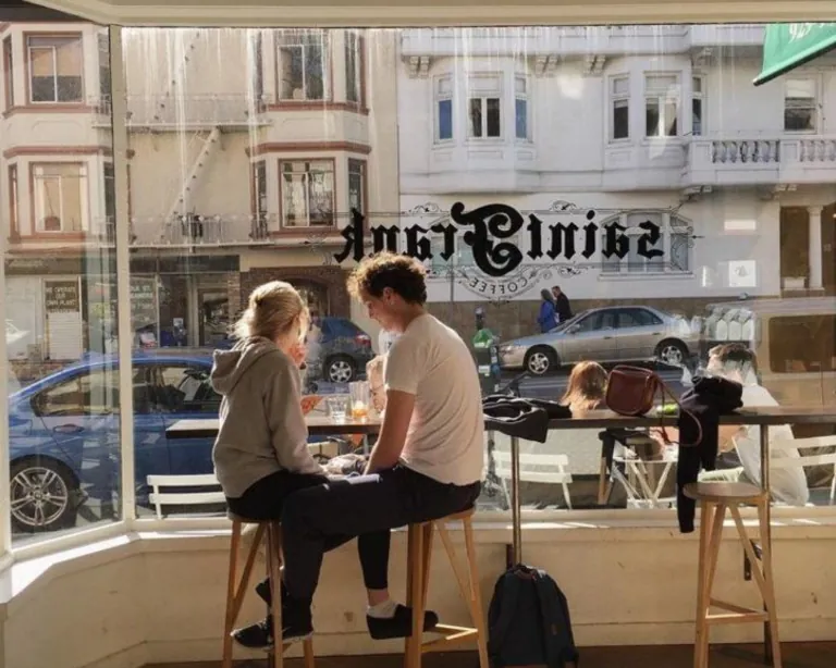 Four people sitting at a window counter in a cafe, talking over lunch