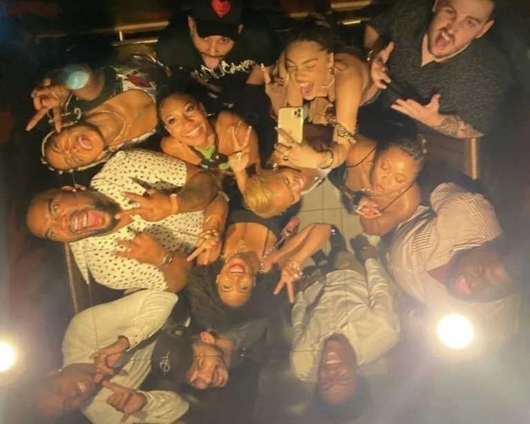 A large group of friends piled together, laughing for a photo on a night out