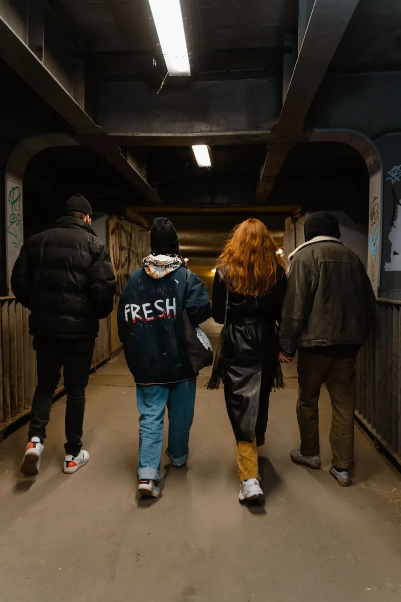 Four friends walking together through a lit underpass at night