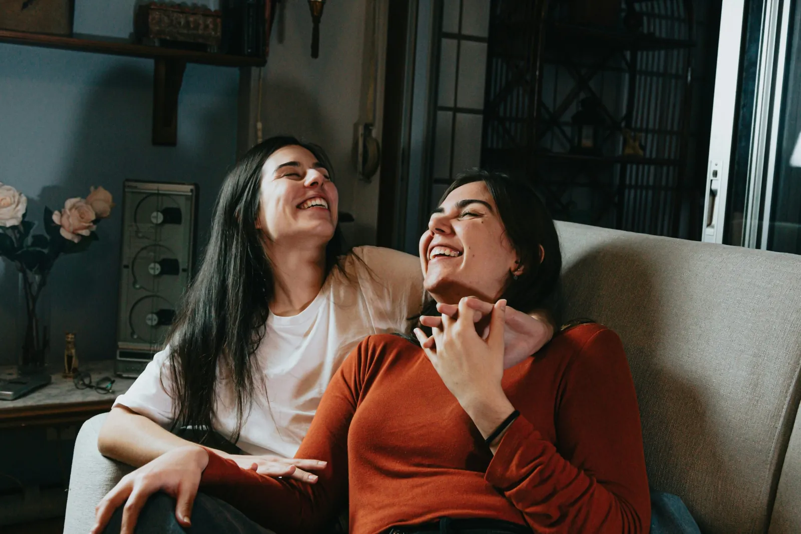 Two friends sitting close together on a sofa, laughing