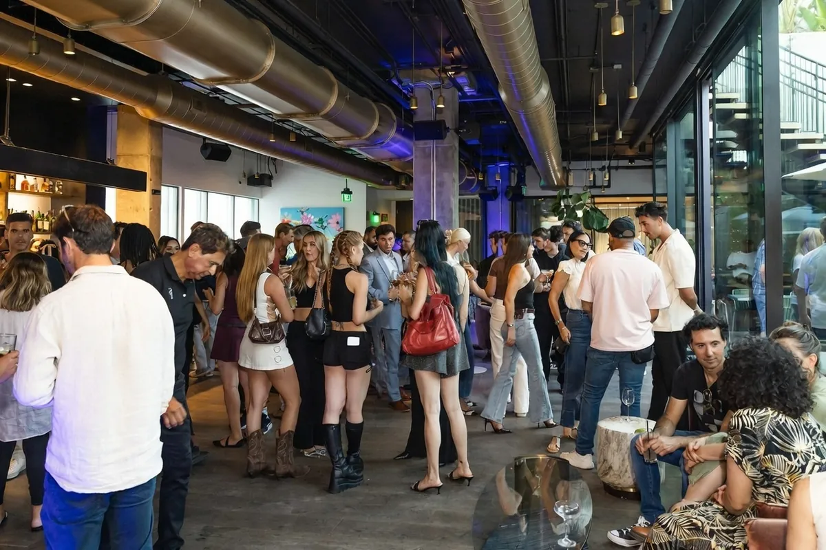 A crowd at a Buffet event on an outdoor patio in Los Angeles, dozens of people talking in the sun