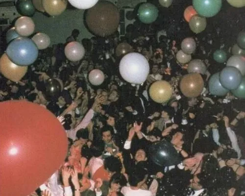 Balloons drifting above a dense crowd with their hands in the air